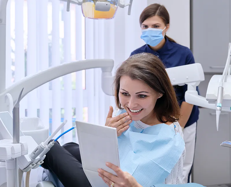 Patienten beim Zahnarzt schaut glücklich in den Spiegel